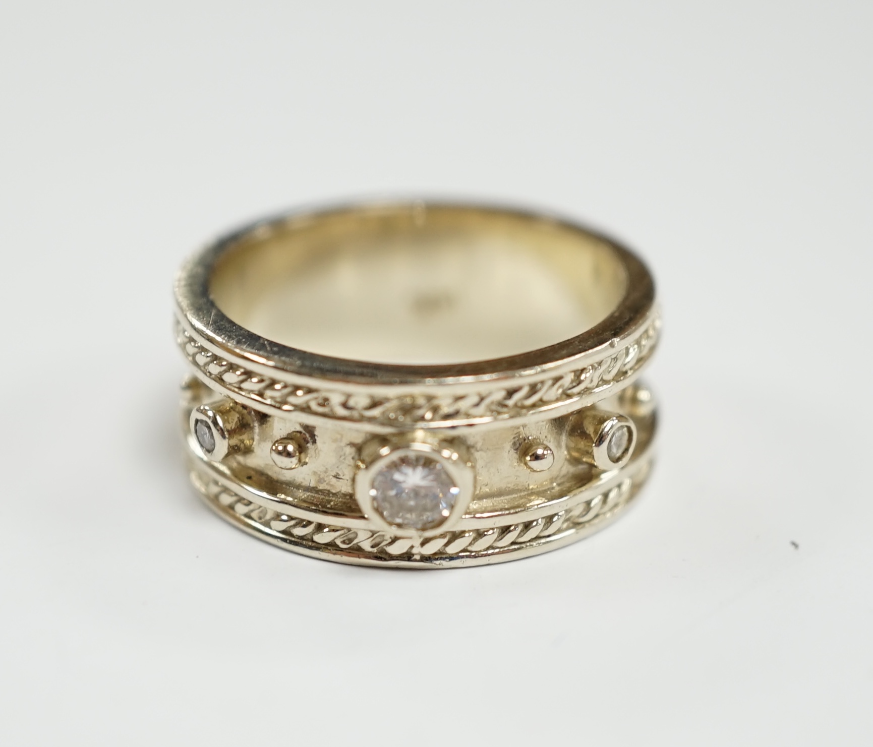A modern 14k white metal and three stone collet set diamond set band, size M, gross weight 7.5 grams.